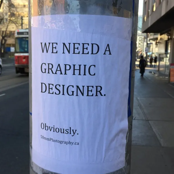A notice on a pole: We need a graphic designer. Obviously.